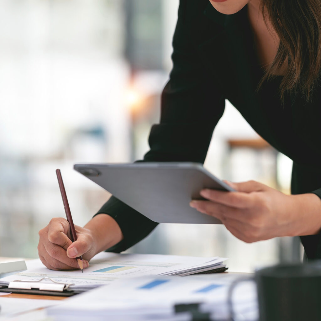 A cropped stock image of Project managers working on a project, holding a tablet and pencil making notes.