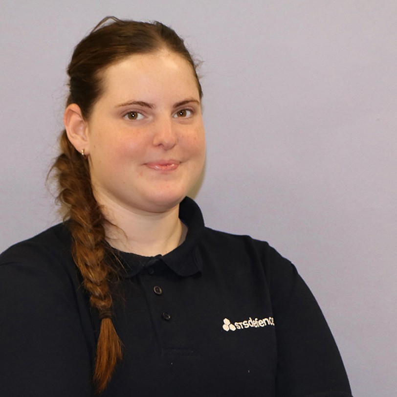 A cropped image of a female STS Defence apprentice against a grey wall.