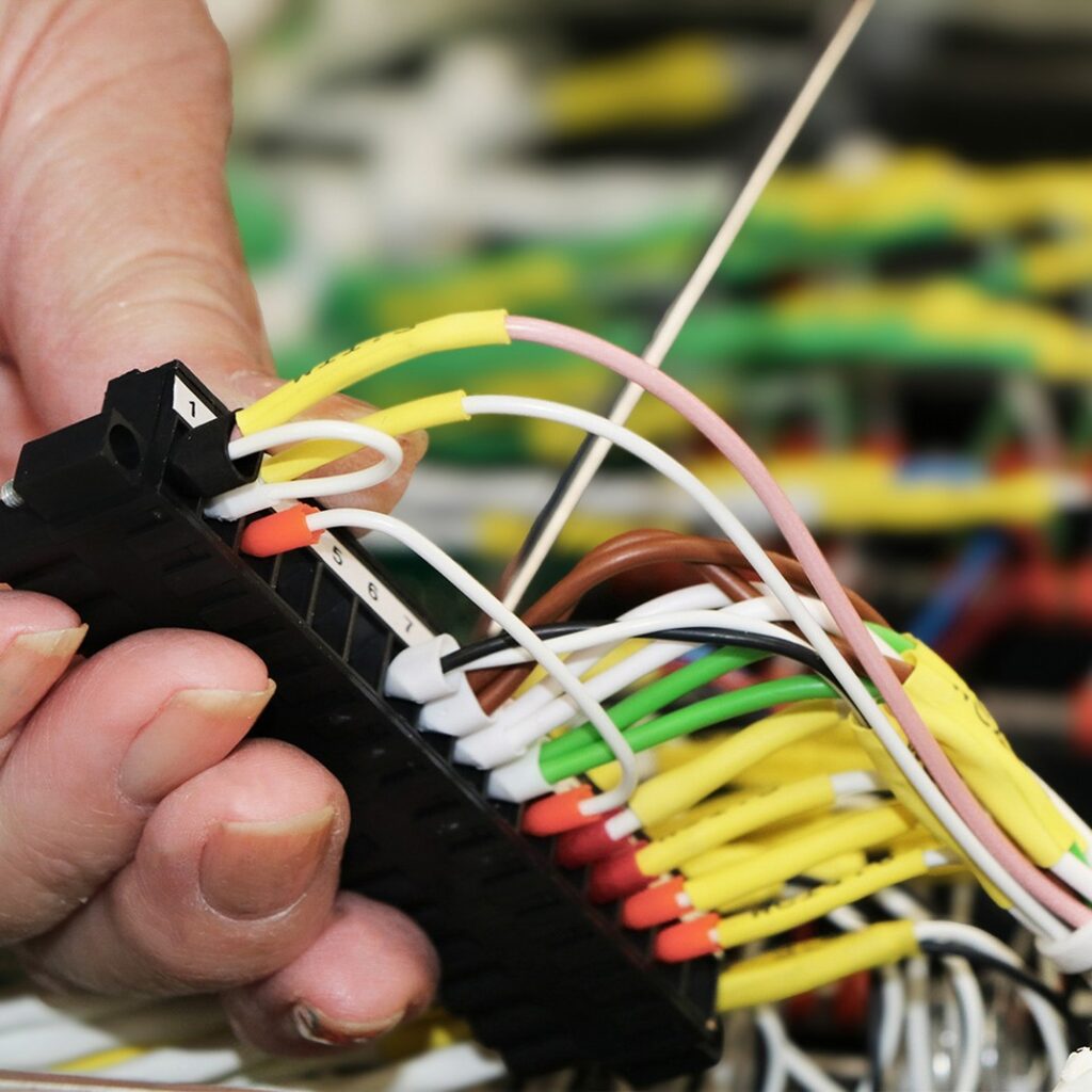 A cropped close-up of an STS Defence employee working on wiring.