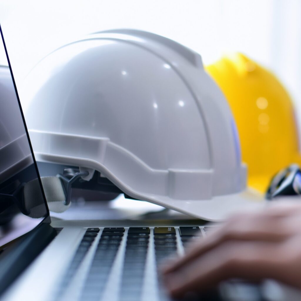 A cropped stock image of a Health & Safety Engineer Architect working table with safety helmet.