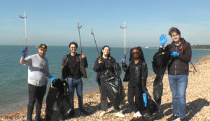 A group of STS Defence volunteers down Stoke Bays participating in a beach clean for World Clean-up Day 2025. They are clutching litter pickers and bags.